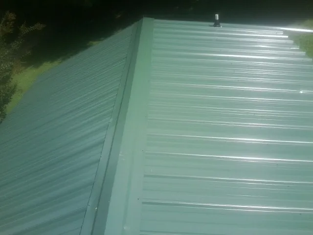 New green metal panels meeting at the ridge of a roof — Flat Roof Repair work by our crew in Thayne