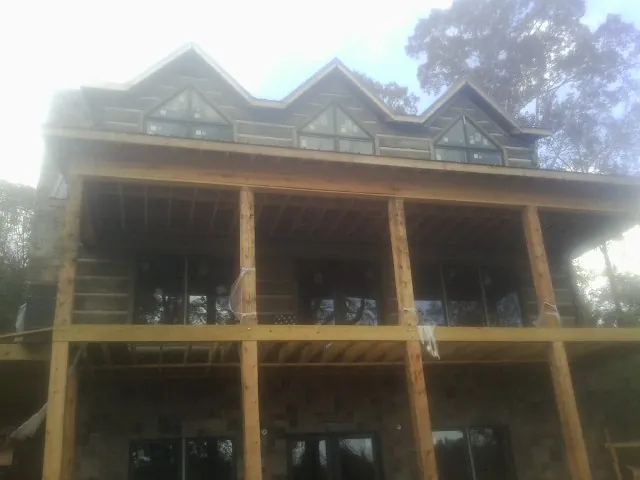 Dormers and porch framing on a large log home under construction — Roof Coating work by our crew in Thayne