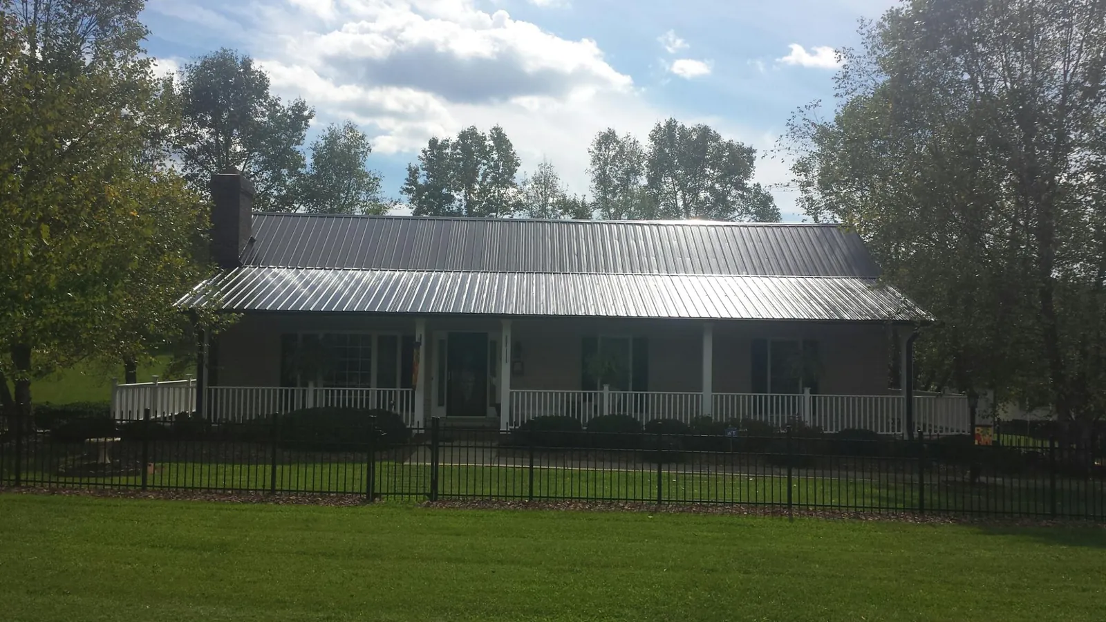 Gray metal roof on a brick ranch with a full width front porch — Gutter Guard Installation work by our crew in Thayne