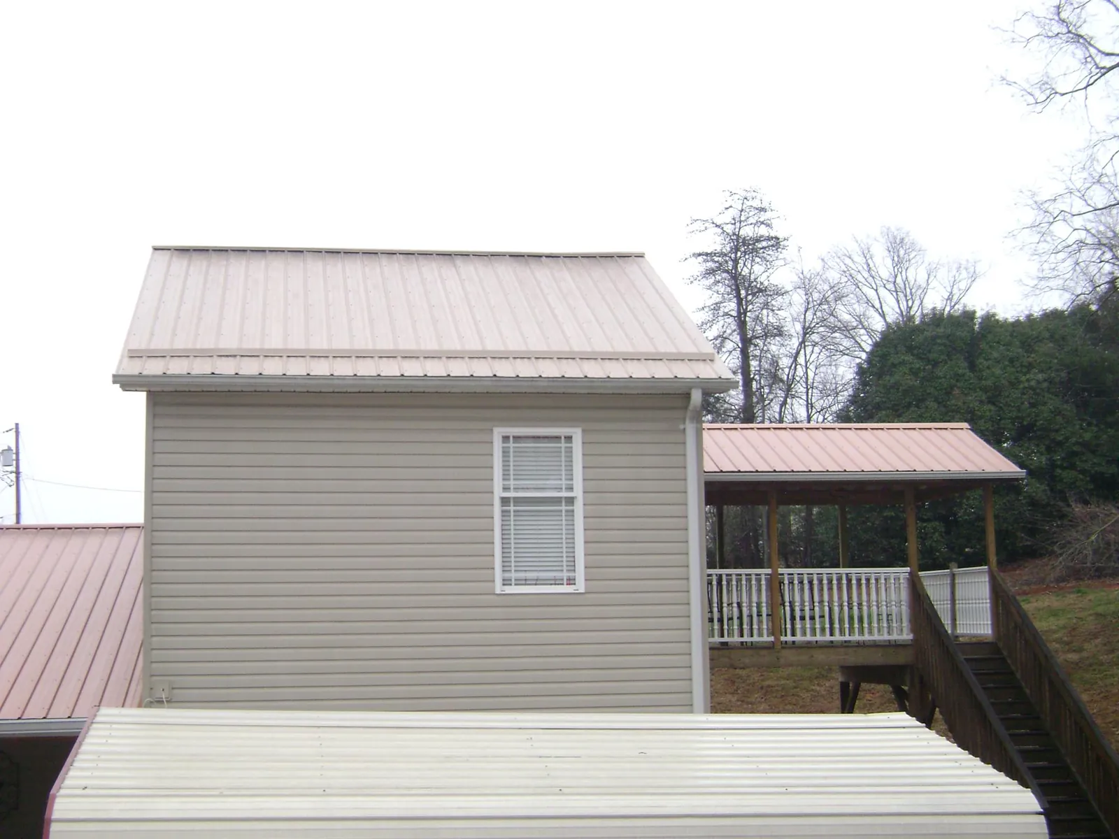 Tan metal roofs on a two story addition and attached porch, from a Roof Replacement job in Thayne