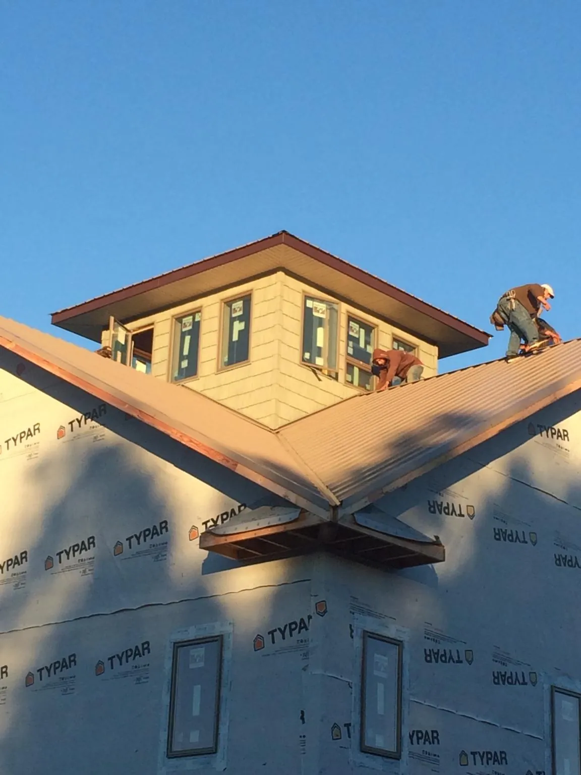 Roofers working around a rooftop cupola on a new metal roof at sunset — Roof Waterproofing in Thayne by Roofing Brothers